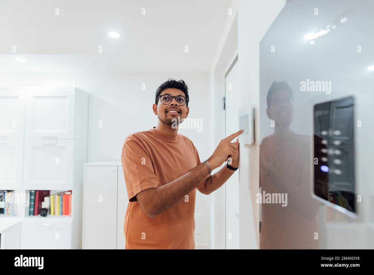 Young man using smart home device on wall Stock Photo