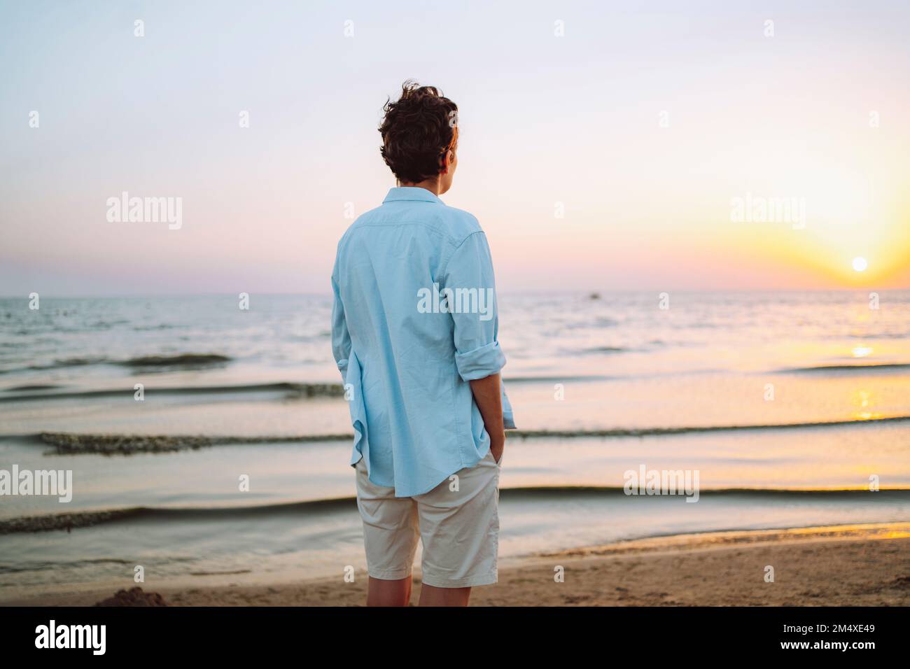 Androgynous woman looking at sea on sunset Stock Photo