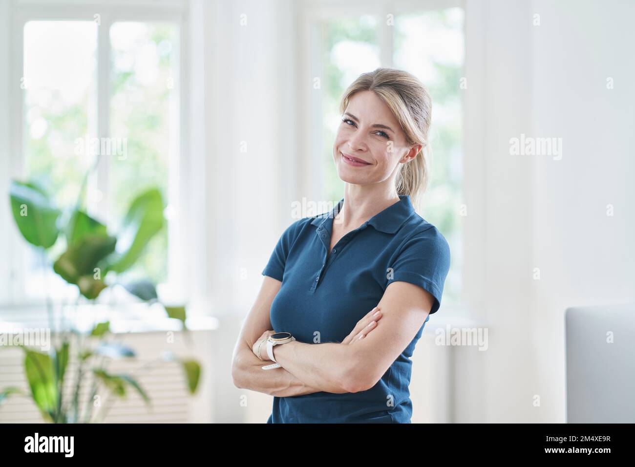 Smiling physical therapist with arms crossed standing in medical
