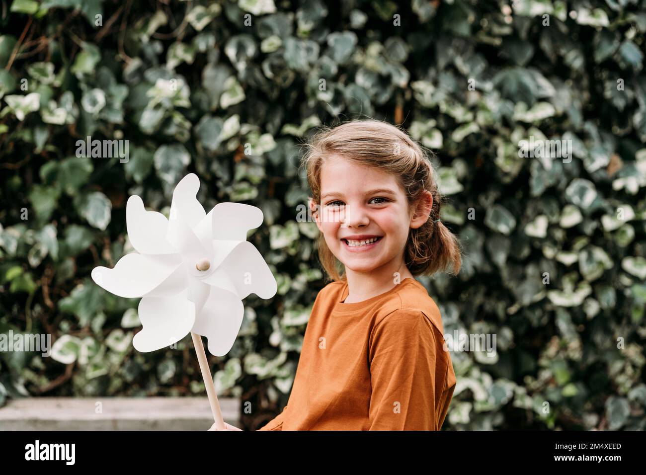 Happy girl with pinwheel toy in front of plant Stock Photo - Alamy