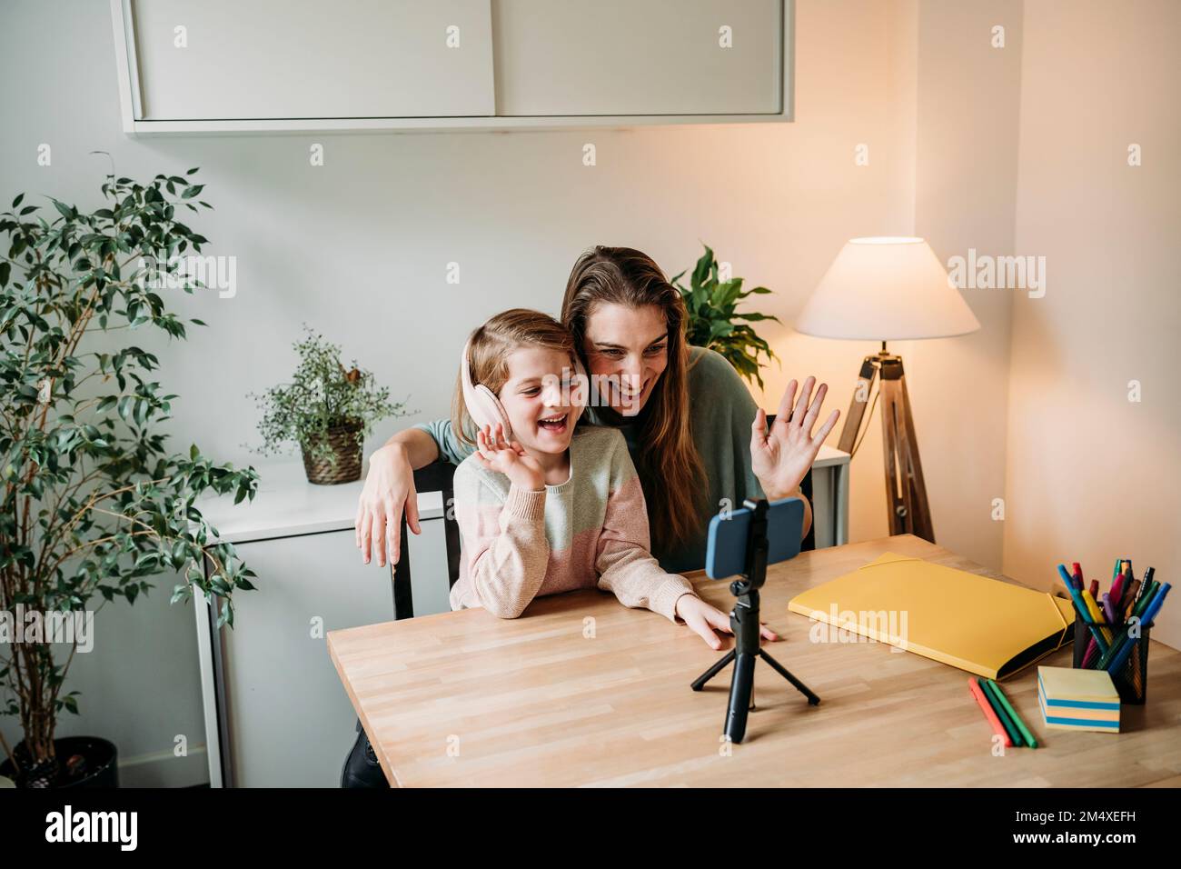 Happy daughter with mother having video call on mobile phone at home ...