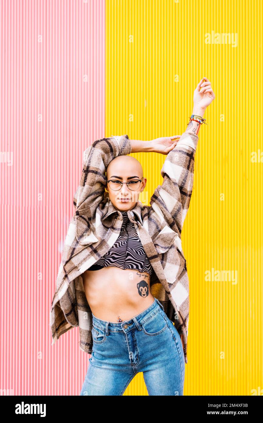 Confident young woman wearing eyeglasses in front of wall Stock Photo