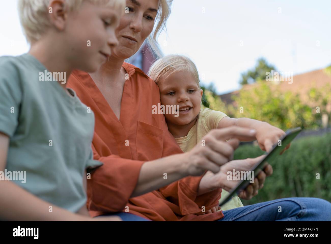 Woman using tablet PC sitting with children Stock Photo