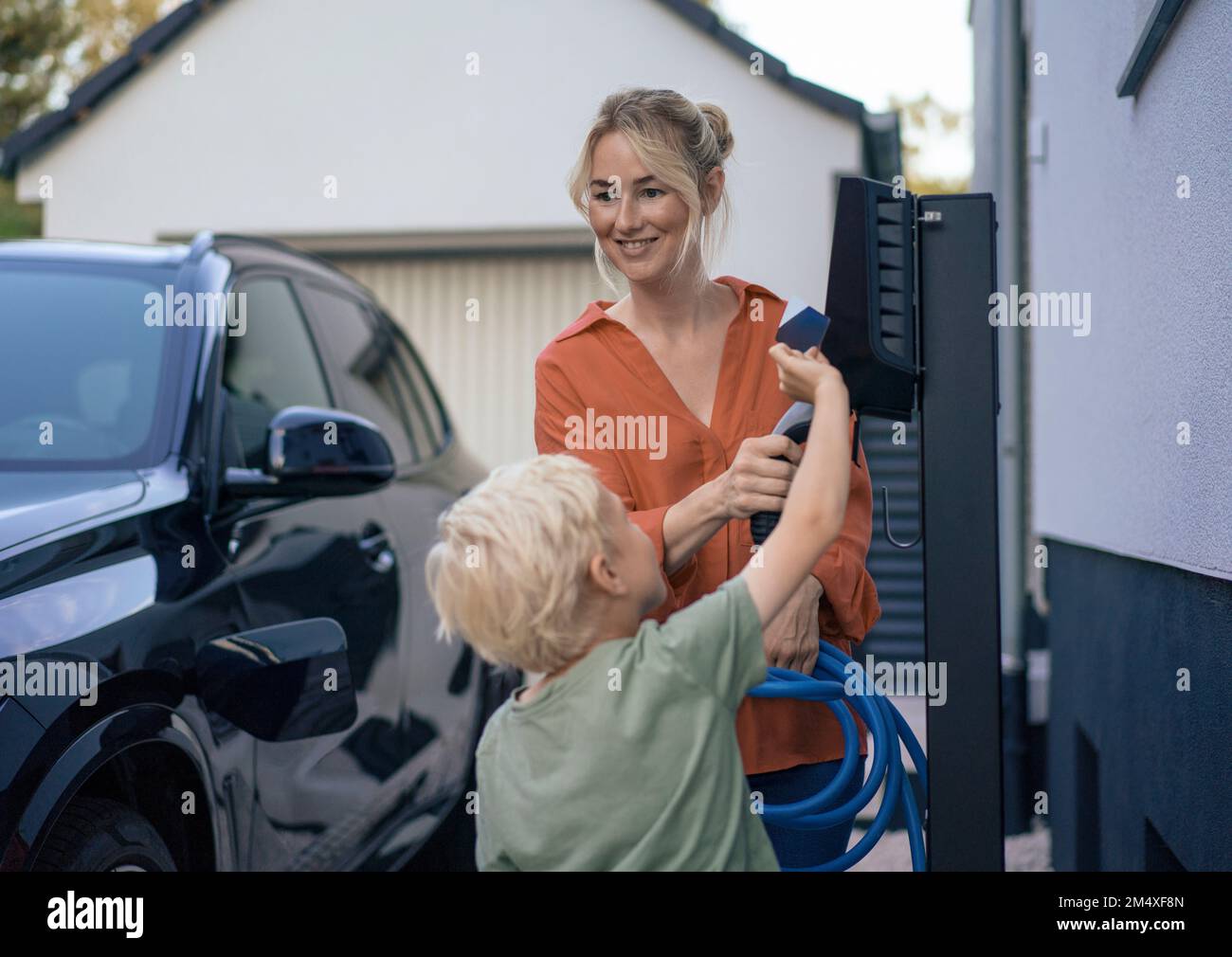 Boy paying through credit card by woman holding electric vehicle