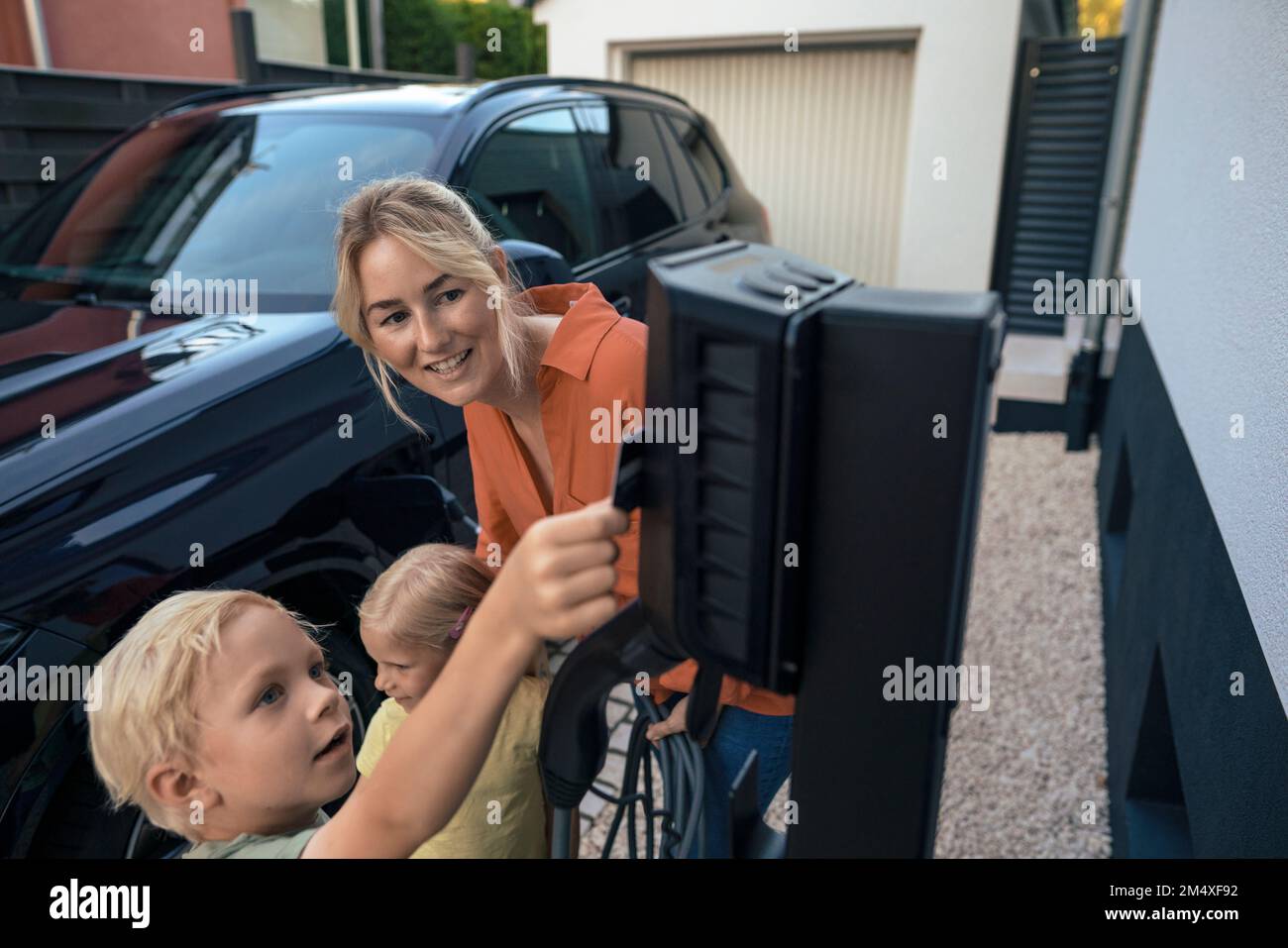 Son paying through credit card by mother holding electric vehicle