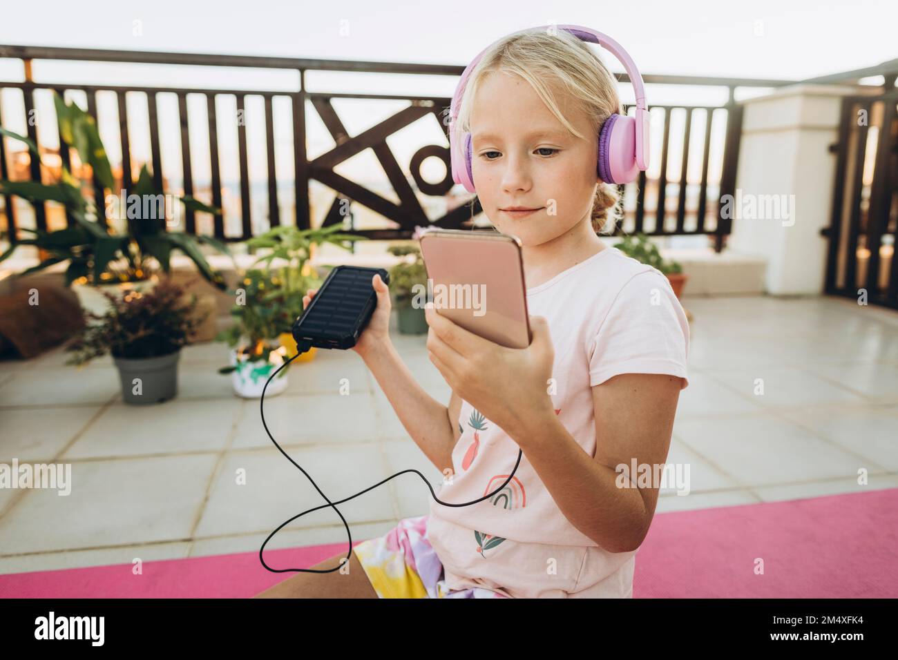 Girl with headphones using mobile phone on terrace Stock Photo