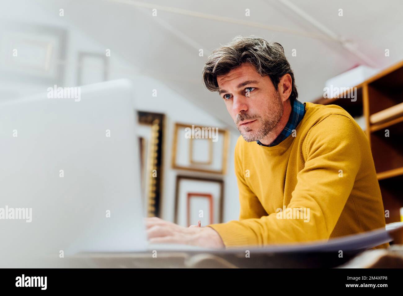 Focused craftsman using laptop at workshop Stock Photo