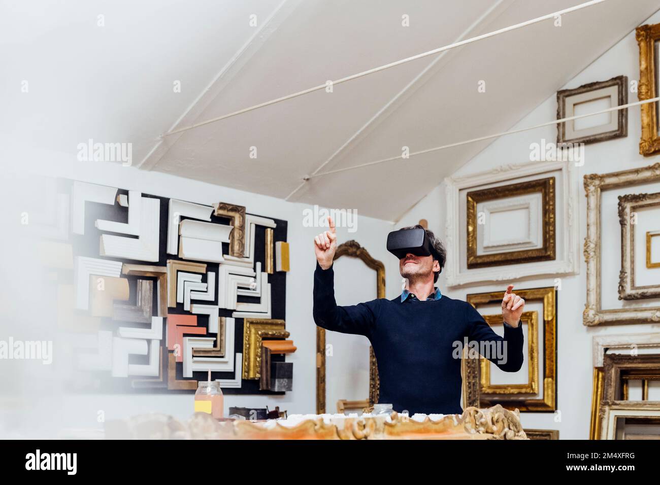 Mature man using virtual reality simulator gesturing in workshop Stock Photo