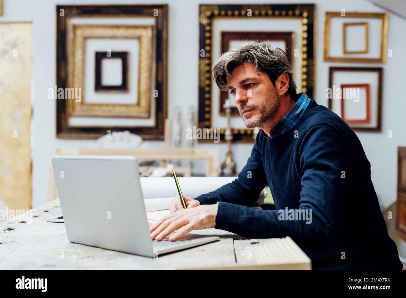 Mature man using laptop working in workshop Stock Photo