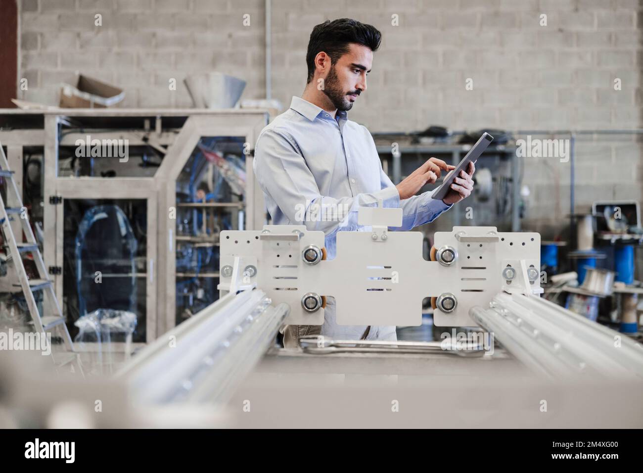 Engineer using tablet PC standing by machinery at industry Stock Photo