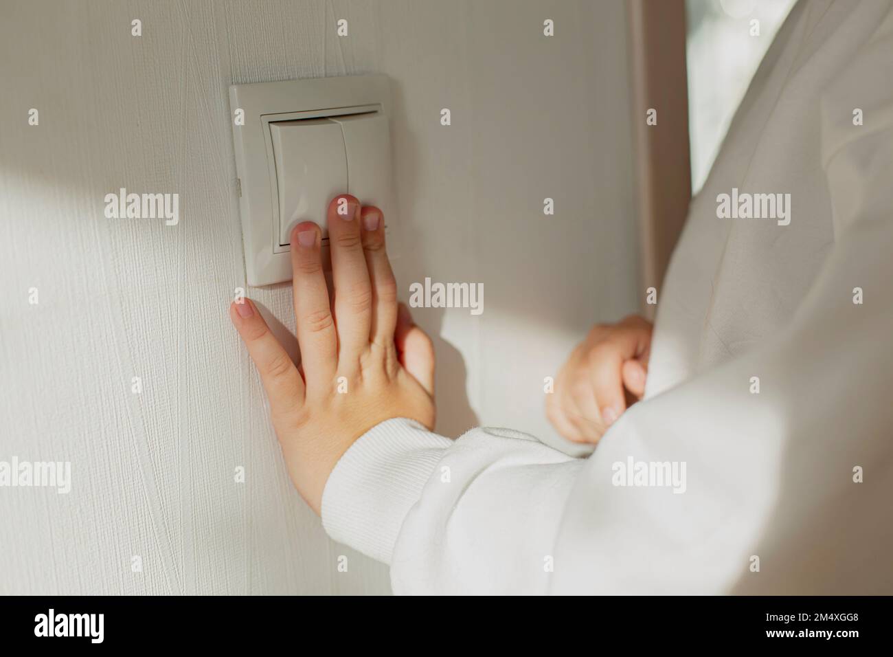 Hand pressing light switch on the wall Stock Photo