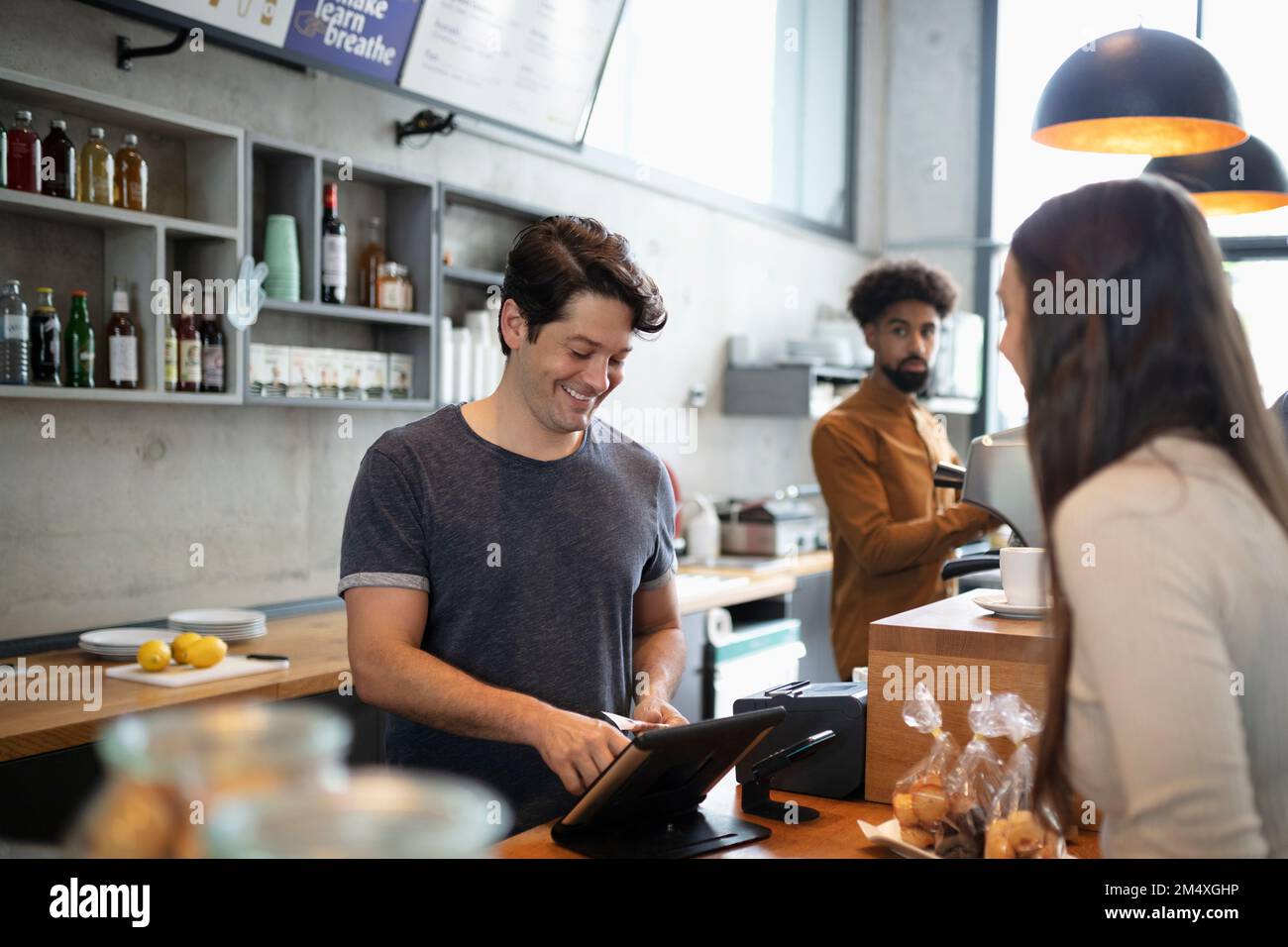 Smiling barista using tablet PC at counter in cafe Stock Photo