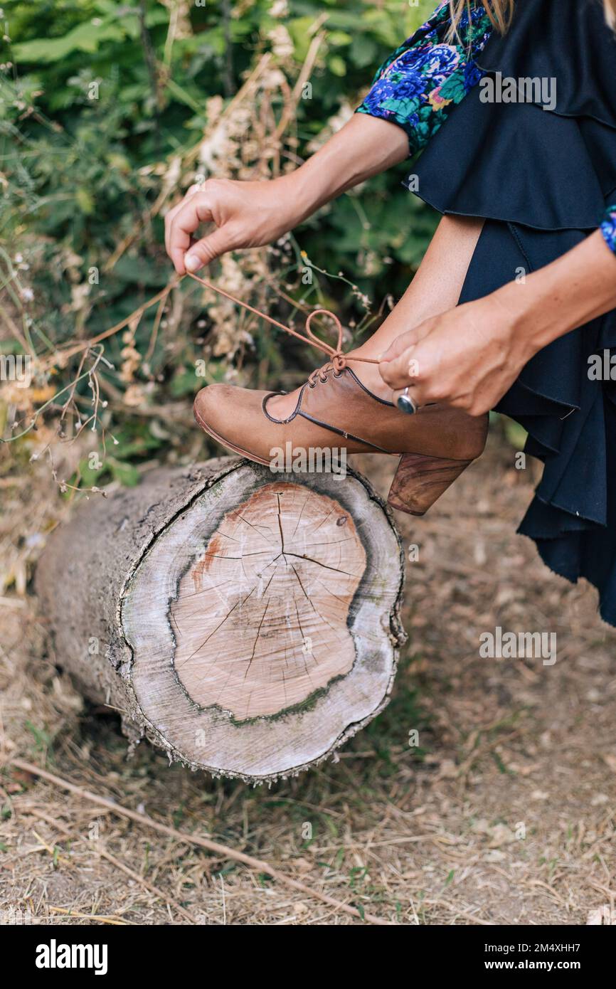 Woman tying shoelace keeping leg on tree stump Stock Photo