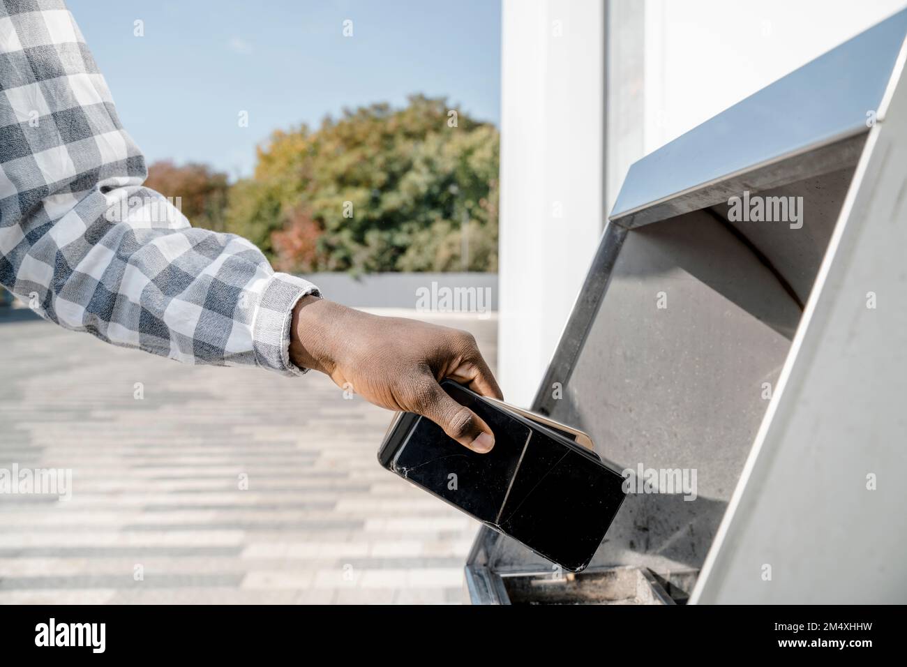 Hand of man throwing mobile phones in garbage bin Stock Photo Alamy
