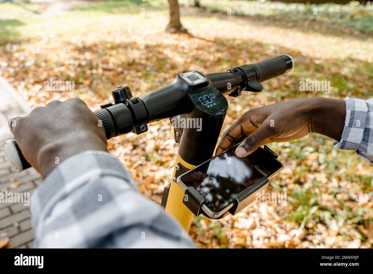Man using mobile app on electric push scooter Stock Photo