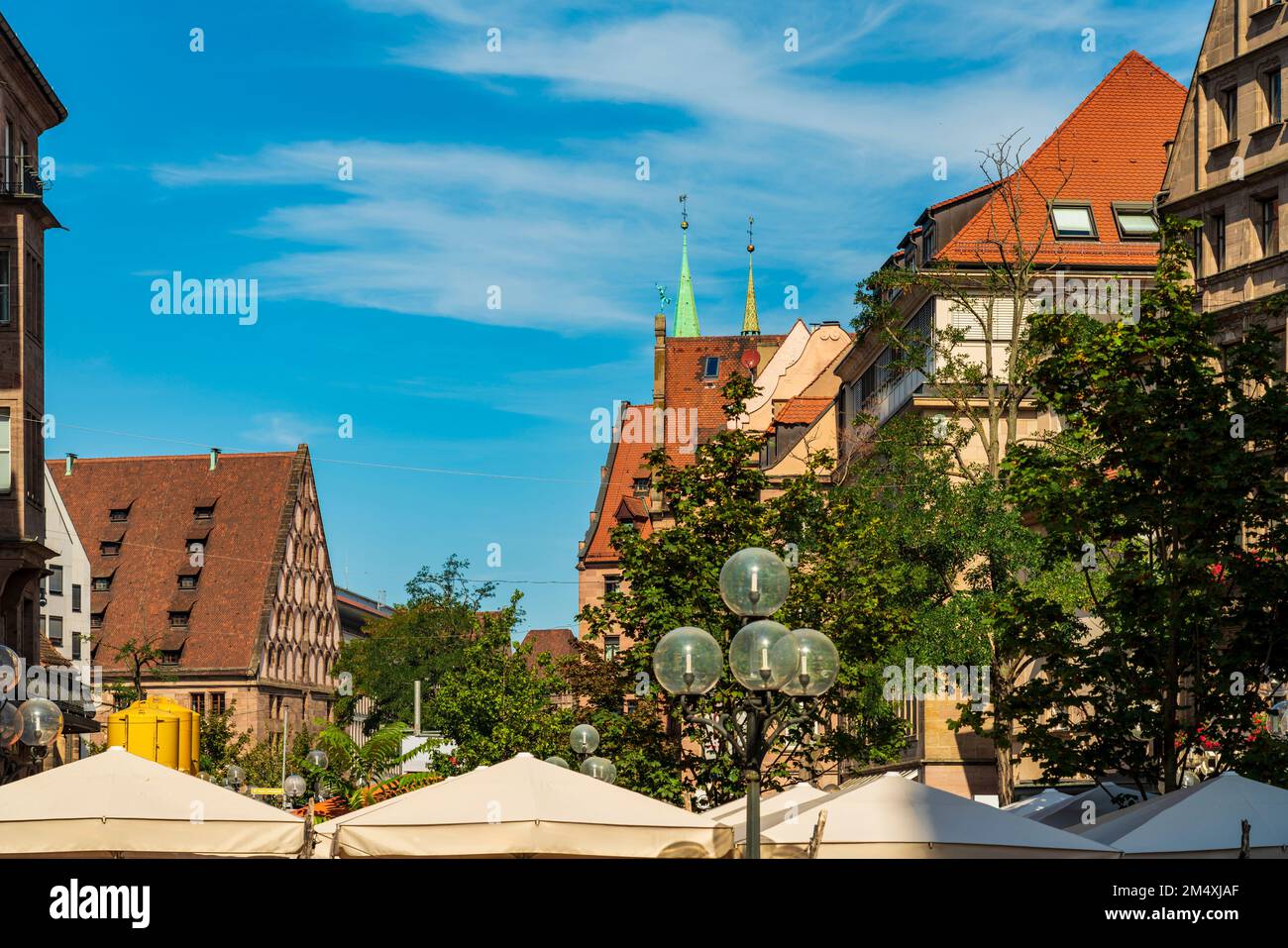 Germany, Bavaria, Nuremberg, Buildings along Konigstrasse with street light and canopies in foreground Stock Photo