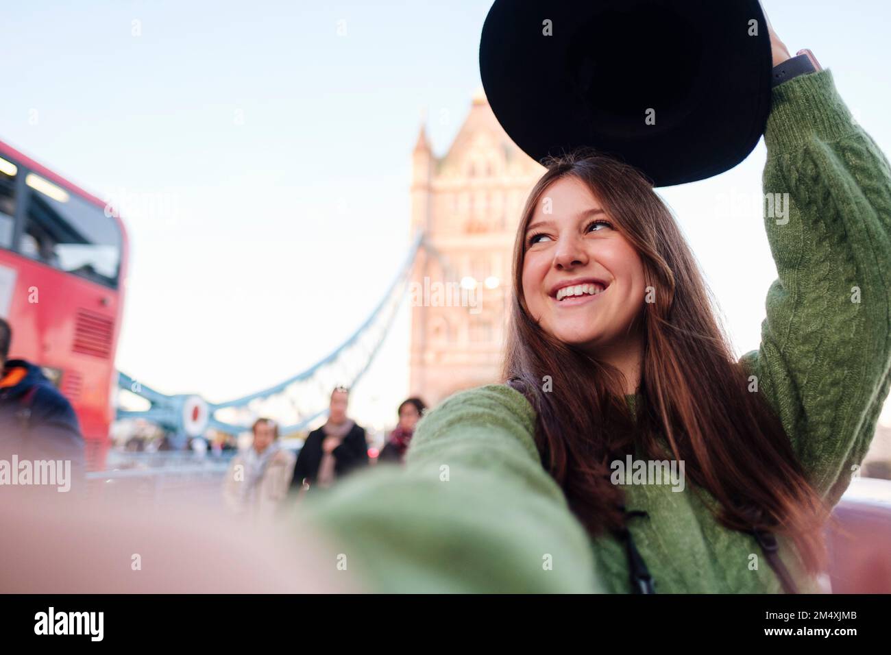 Happy young woman wearing green sweater taking selfie on Tower Bridge