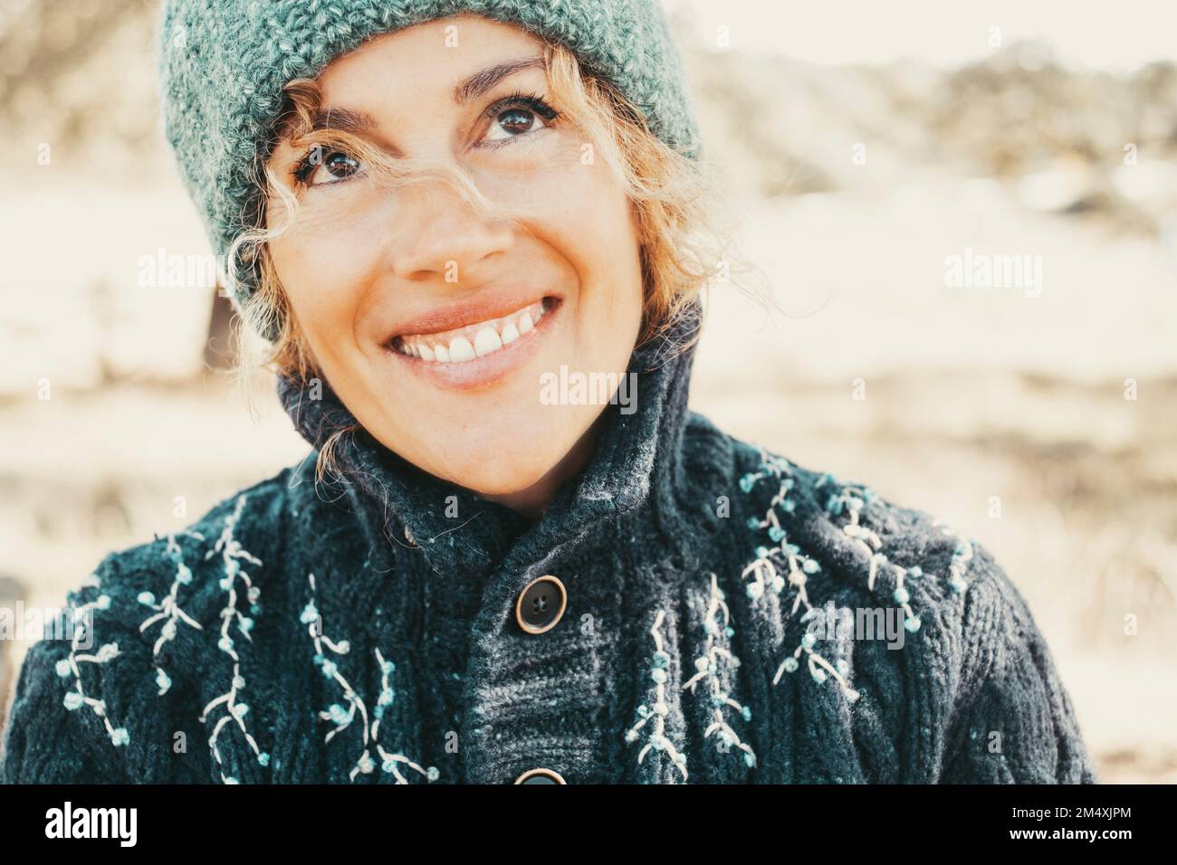 Thoughtful mature woman with toothy smile wearing warm clothing Stock Photo