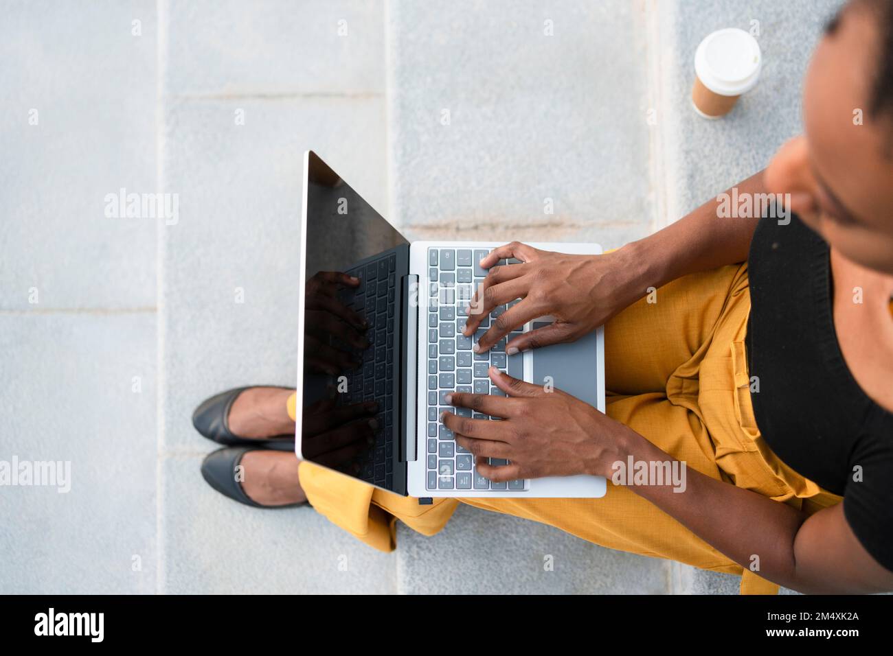 Freelancer working on laptop sitting at staircase Stock Photo