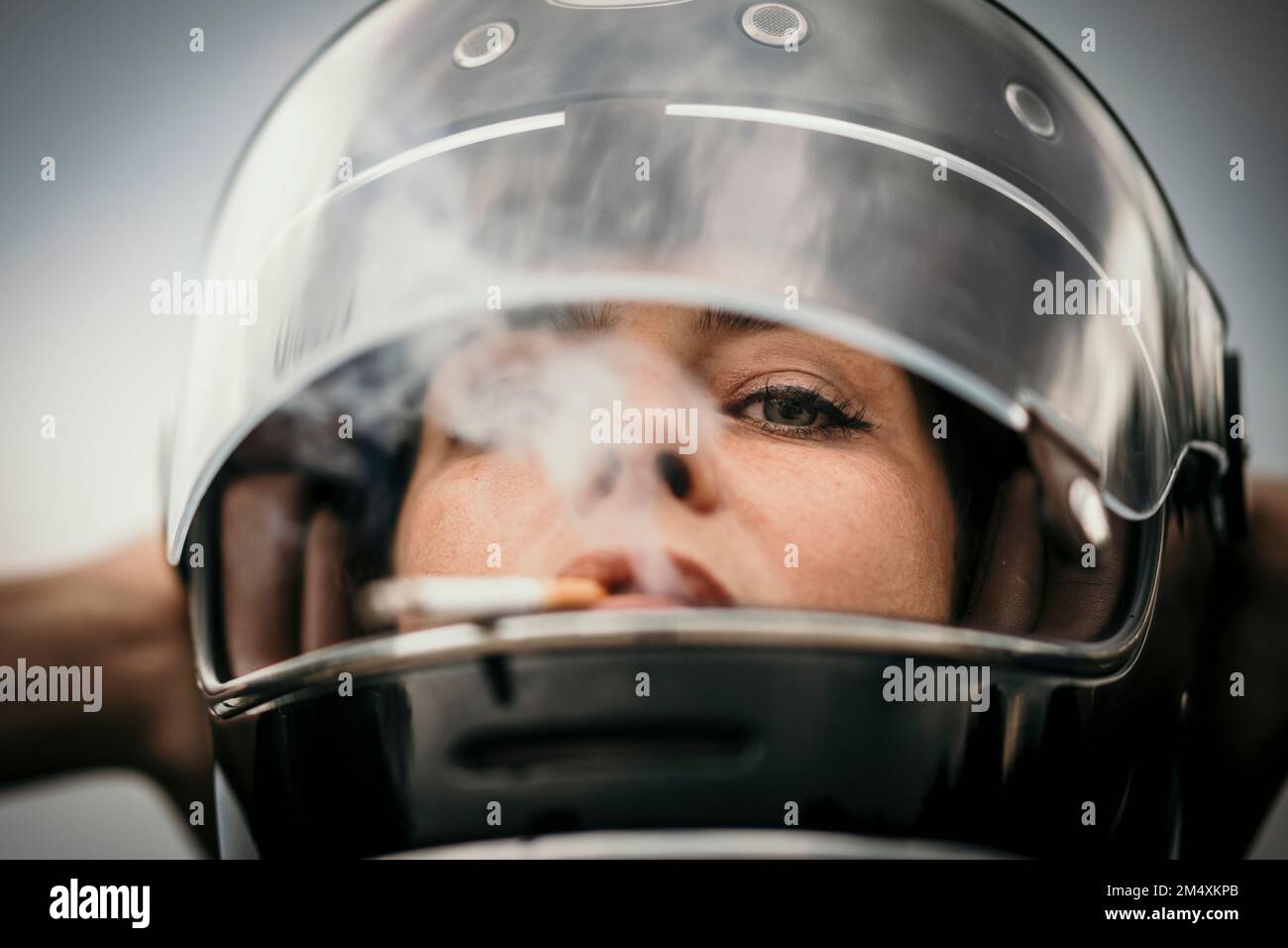Woman wearing helmet smoking cigarette Stock Photo