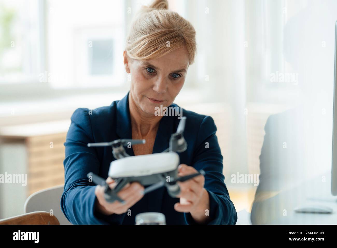 Mature businesswoman analyzing drone at office Stock Photo