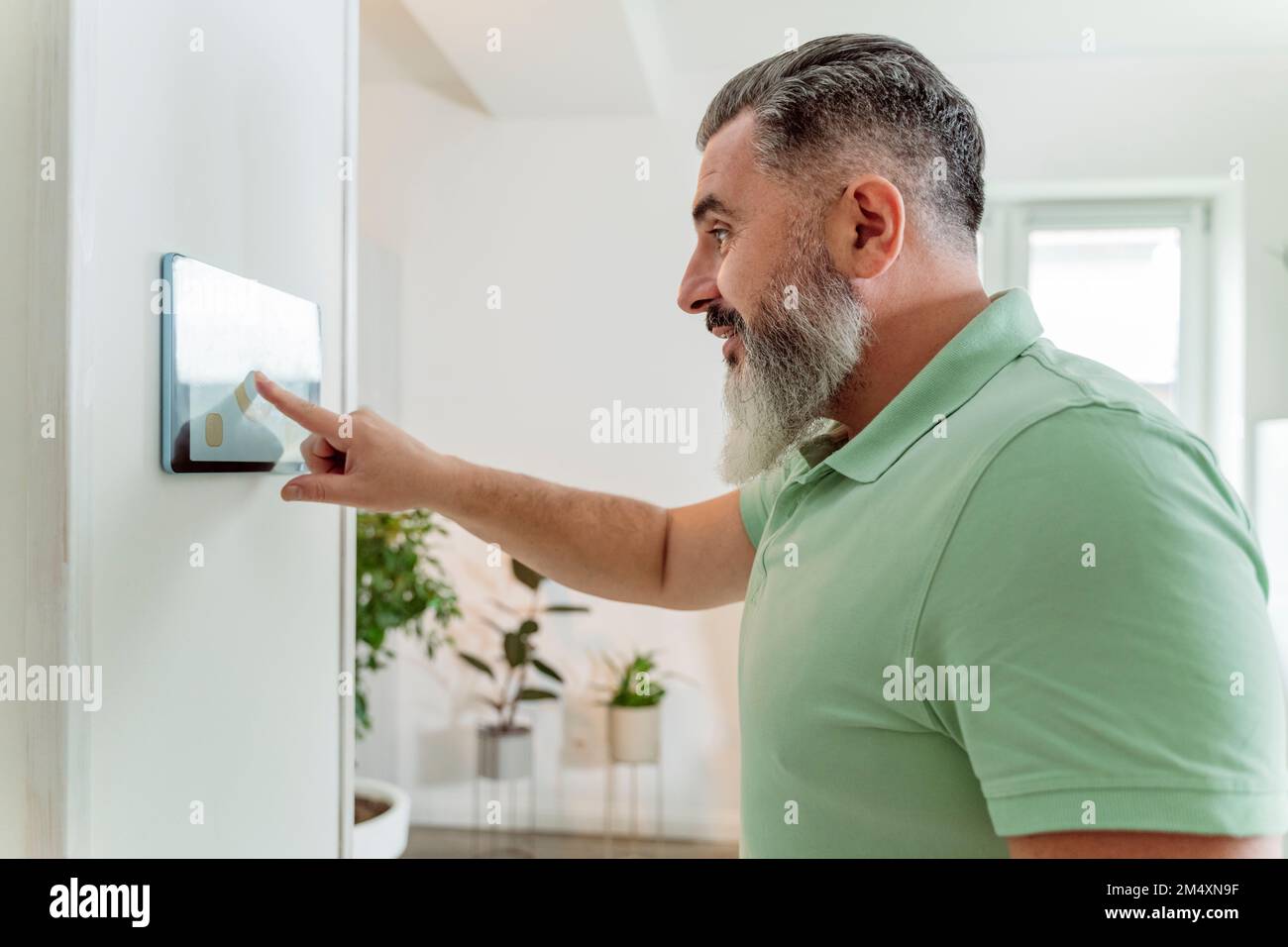 Mature man using tablet PC mounted on wall at home Stock Photo