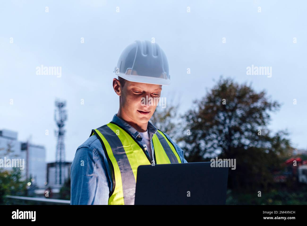 Engineer wearing hardhat using laptop Stock Photo