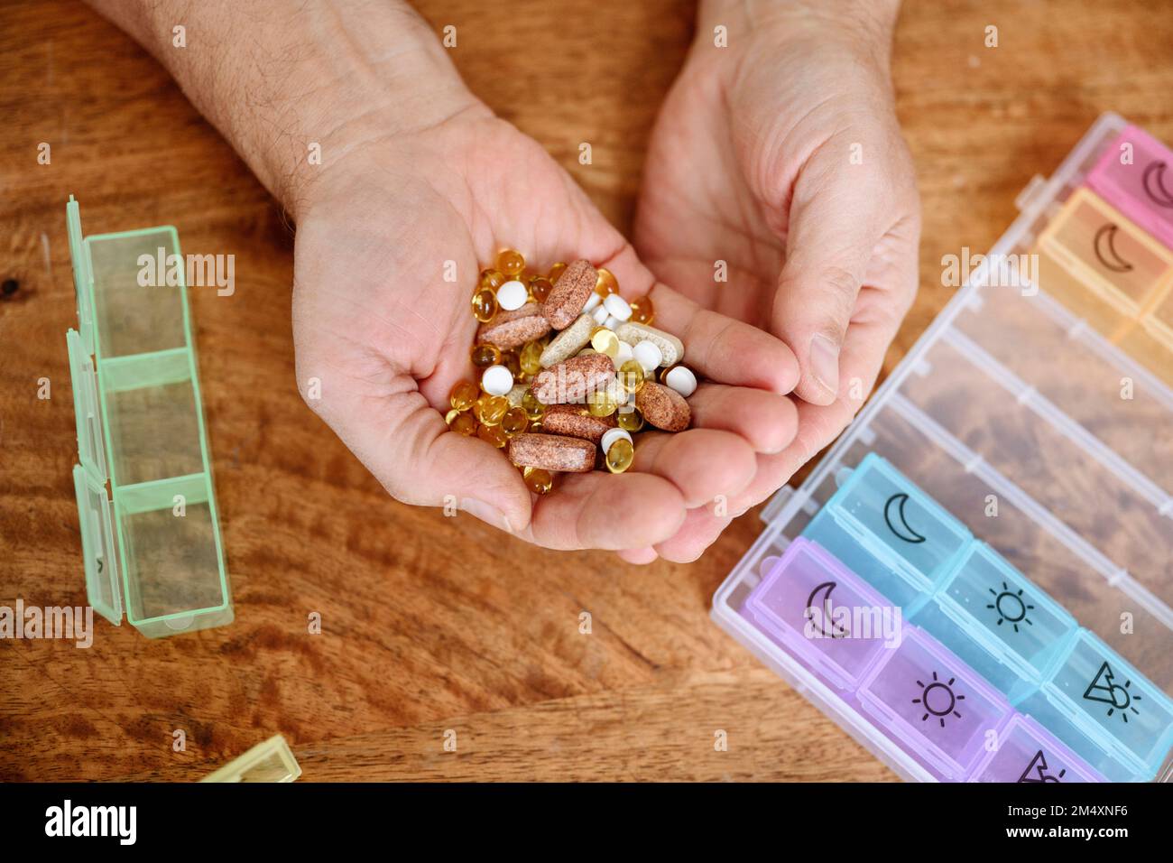 Man holding different pills in hand on table Stock Photo