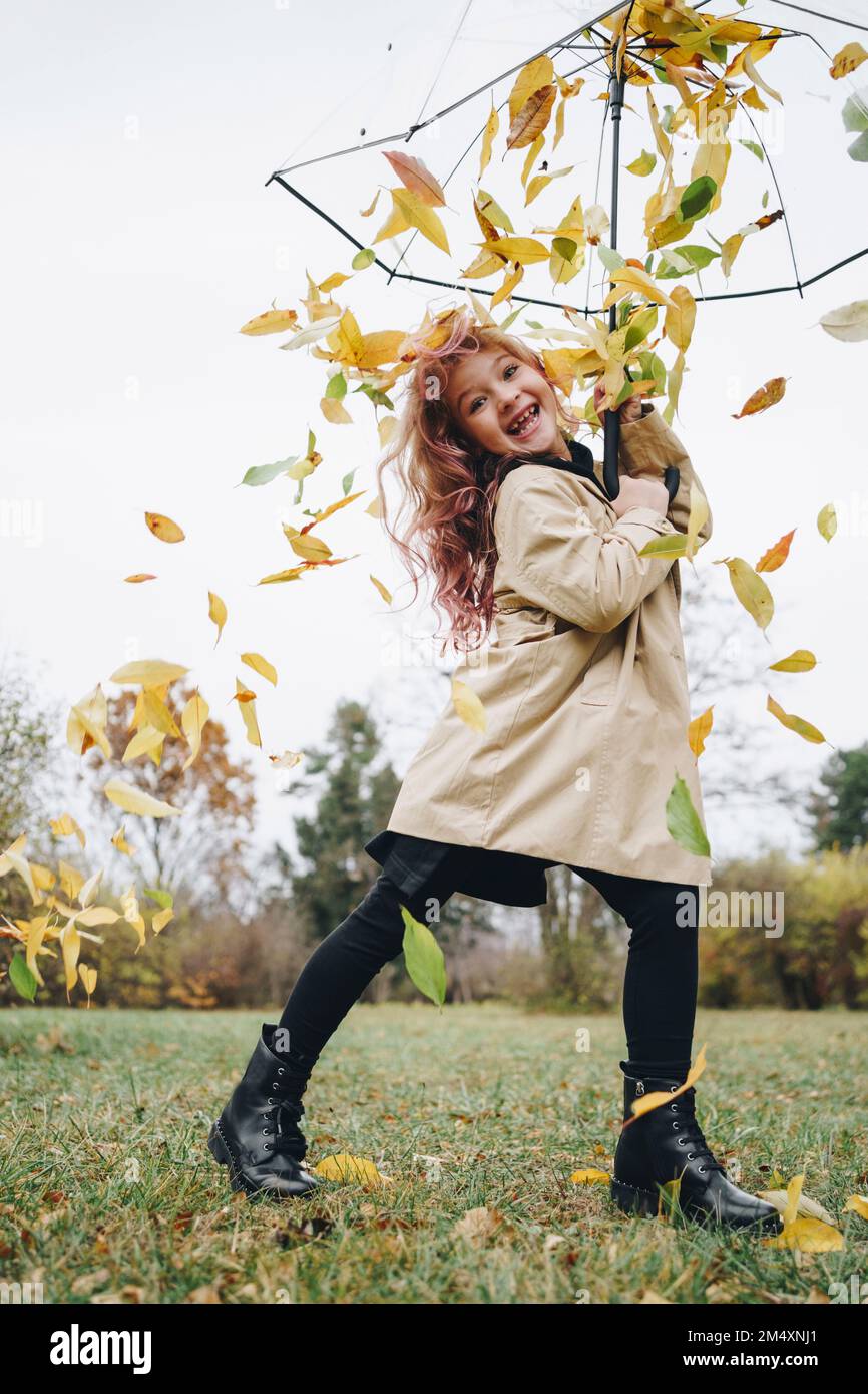 Happy girl holding umbrella with leaves falling in park Stock Photo - Alamy