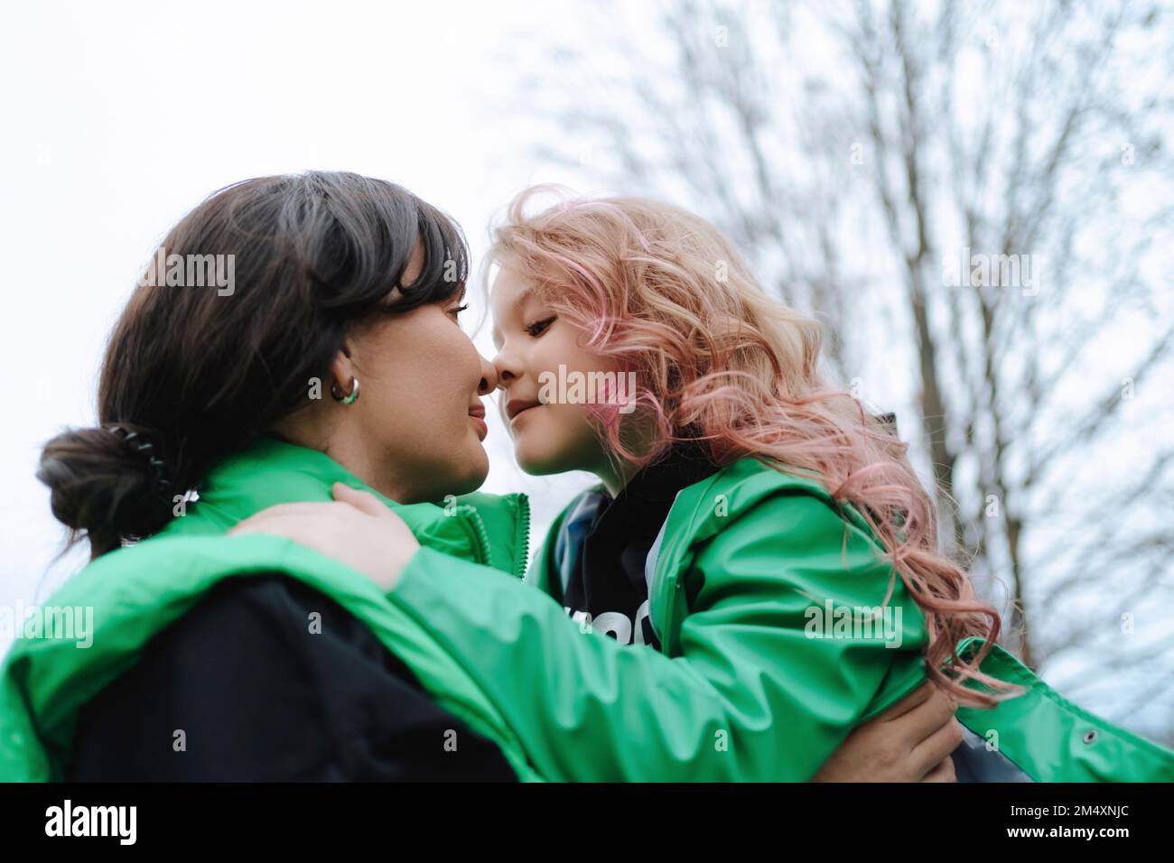 Mother embracing daughter with pink hair at park Stock Photo