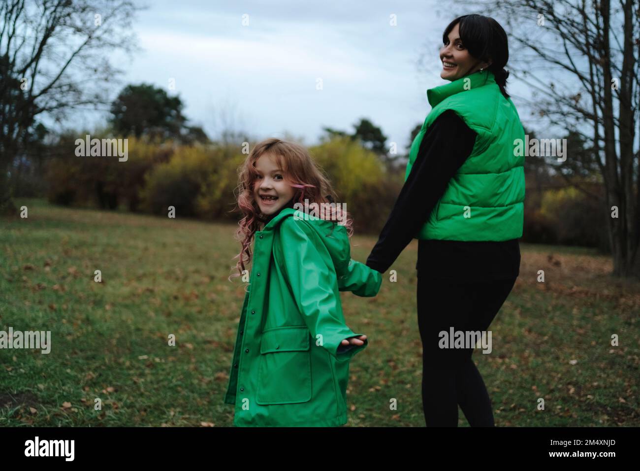 Happy girl holding hands with mother walking in park Stock Photo - Alamy