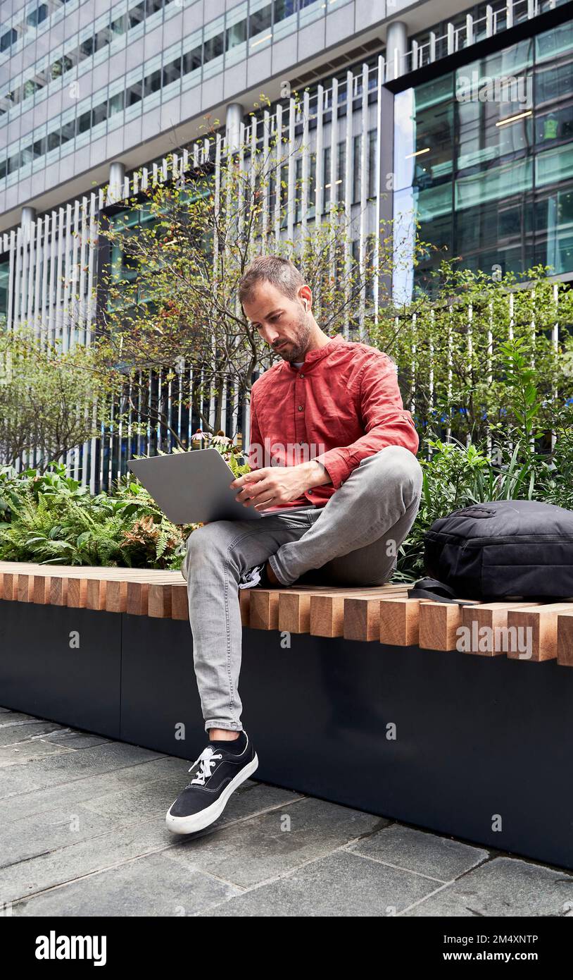 Man using laptop on bench Stock Photo