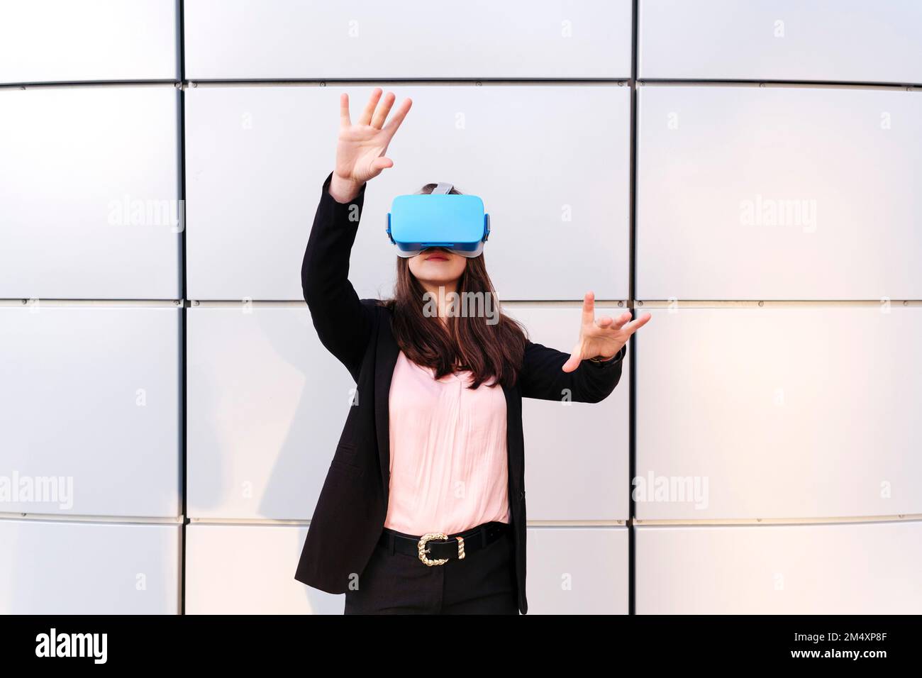 Young woman wearing virtual reality simulator gesturing in front of ...