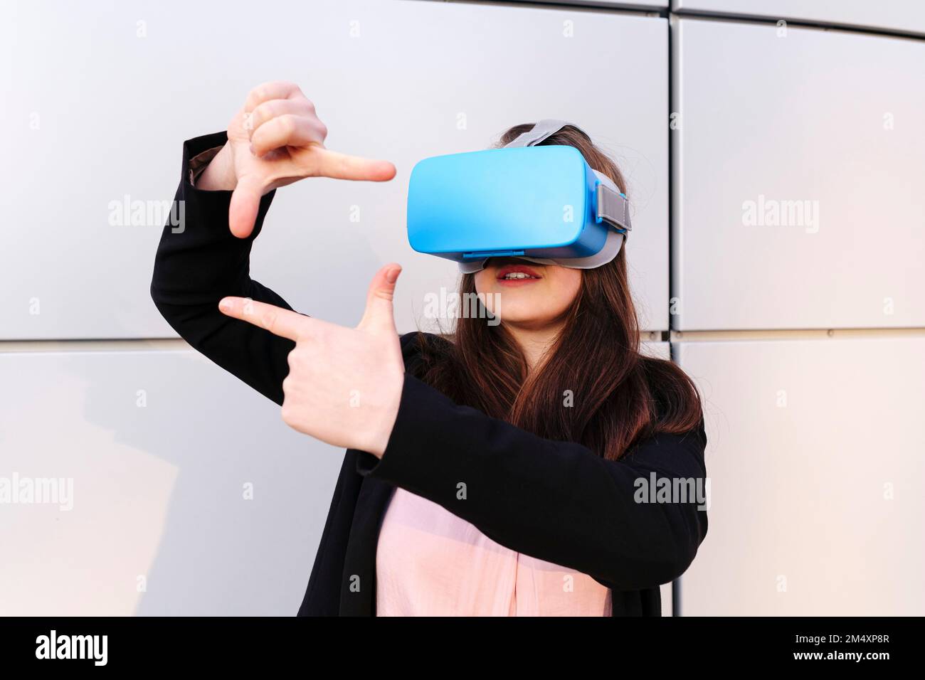 Young woman wearing virtual reality simulator gesturing in front of ...