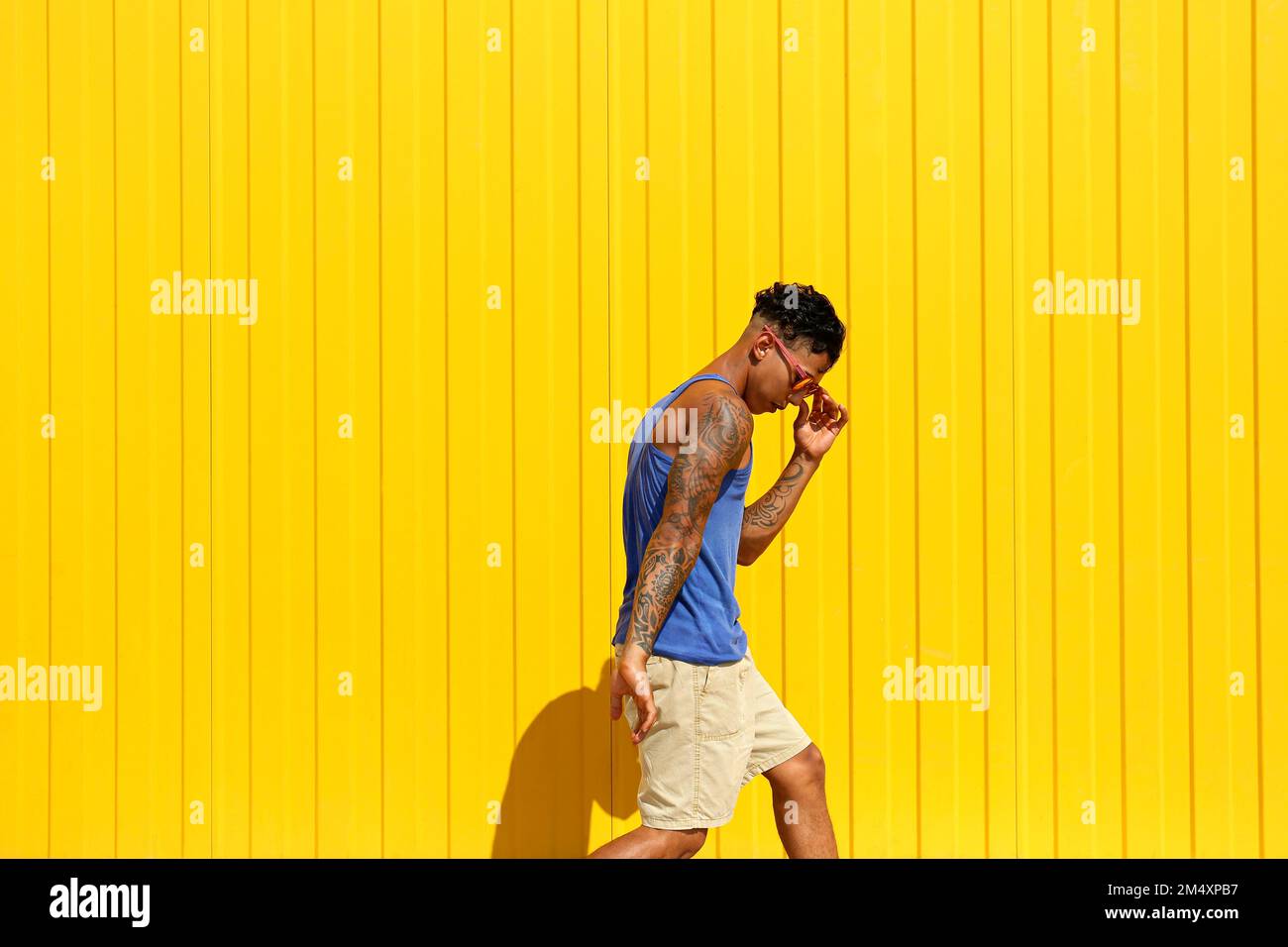 Young man dancing in front of yellow wall Stock Photo
