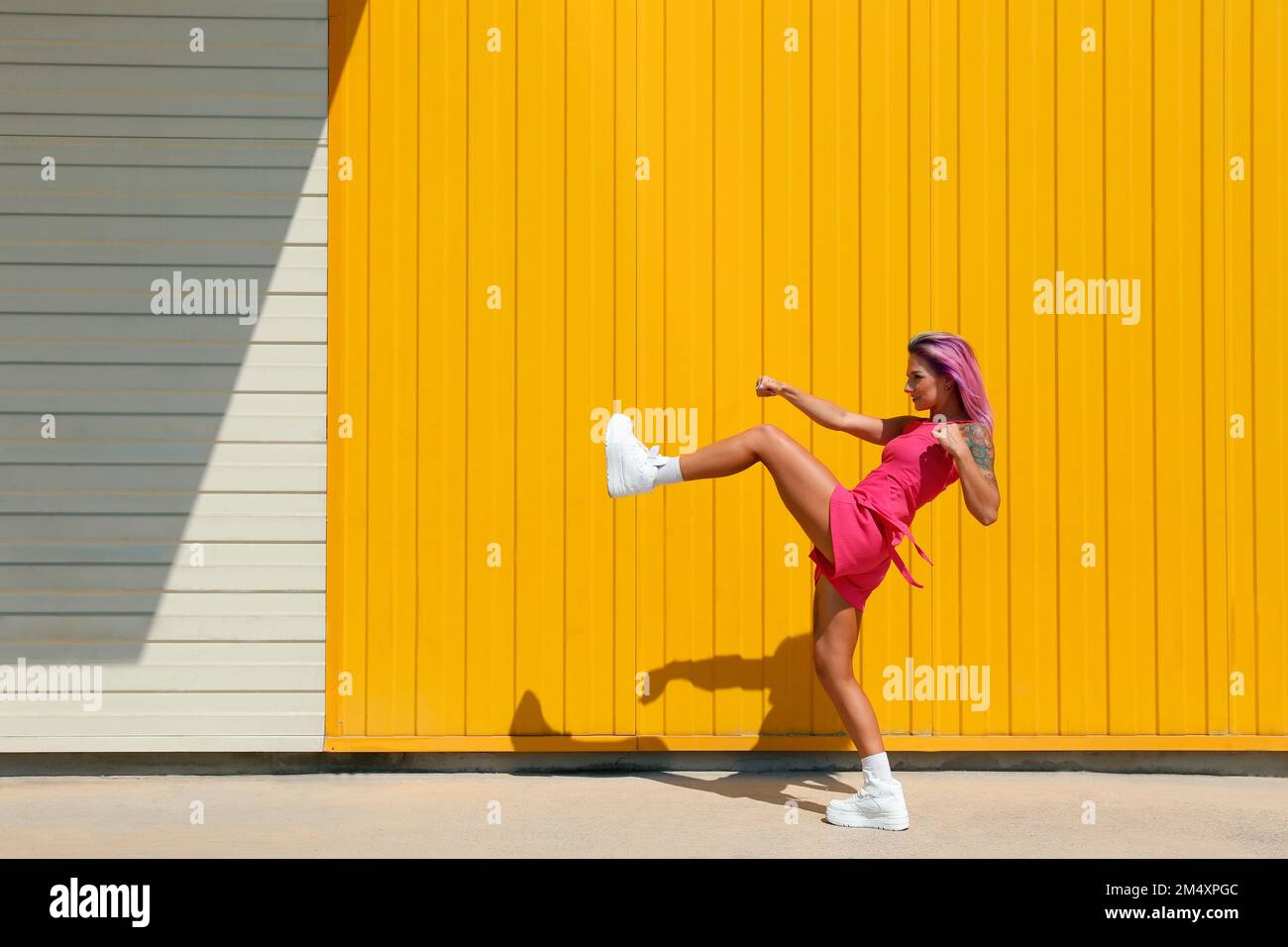 Young woman kicking in front of yellow wall Stock Photo Alamy