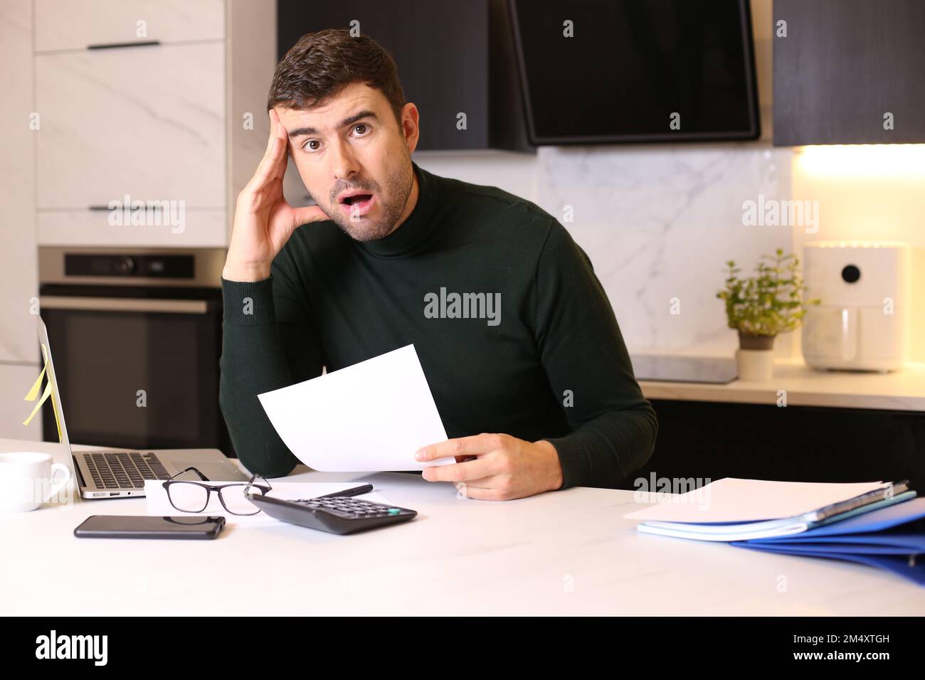 Worried looking man holding document while working from home office Stock Photo