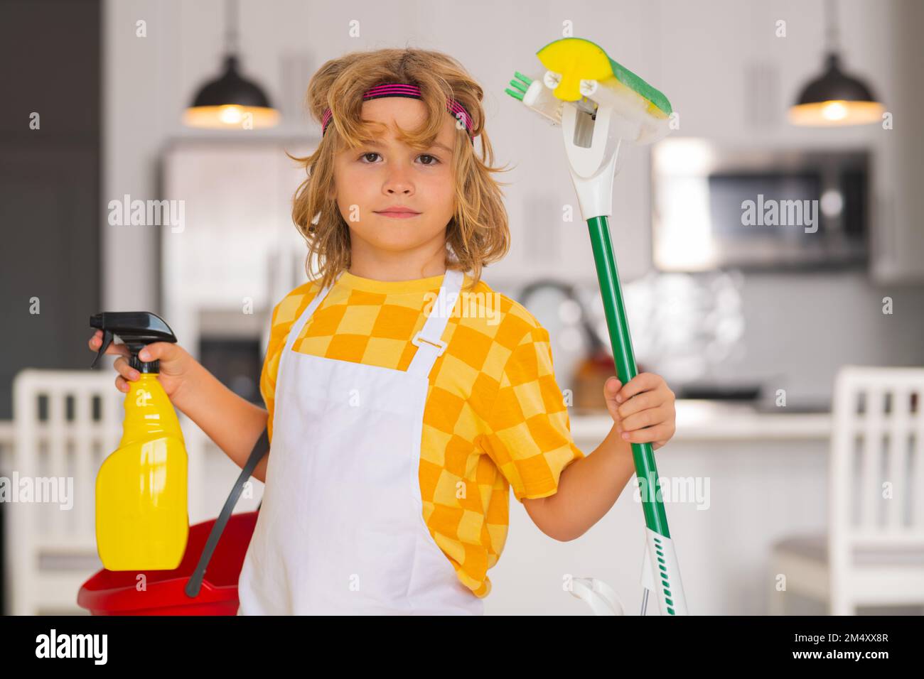 Children helping with housekeeping, cleaning the house. Housekeeping at home. Cute child boy helping with housekeeping on kitchen interior backdround. Stock Photo
