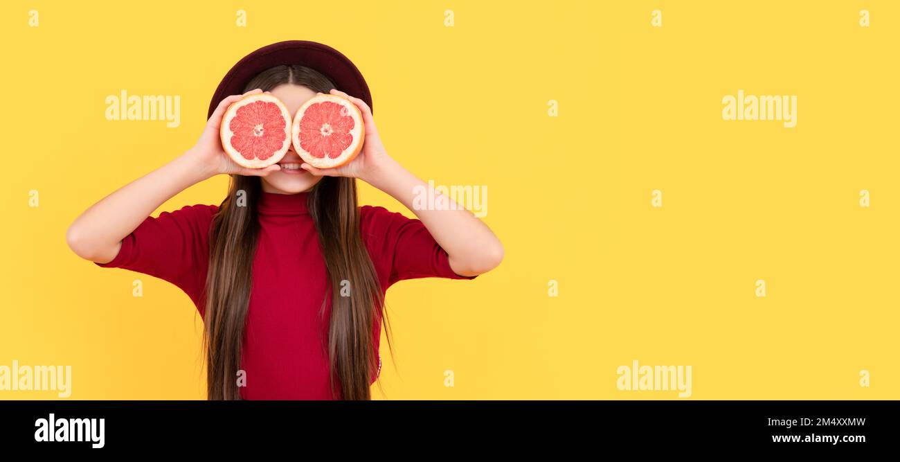 smiling kid behind grapefruit on yellow background, antioxidants. Child girl portrait with grapefruit orange, horizontal poster. Banner header with Stock Photo