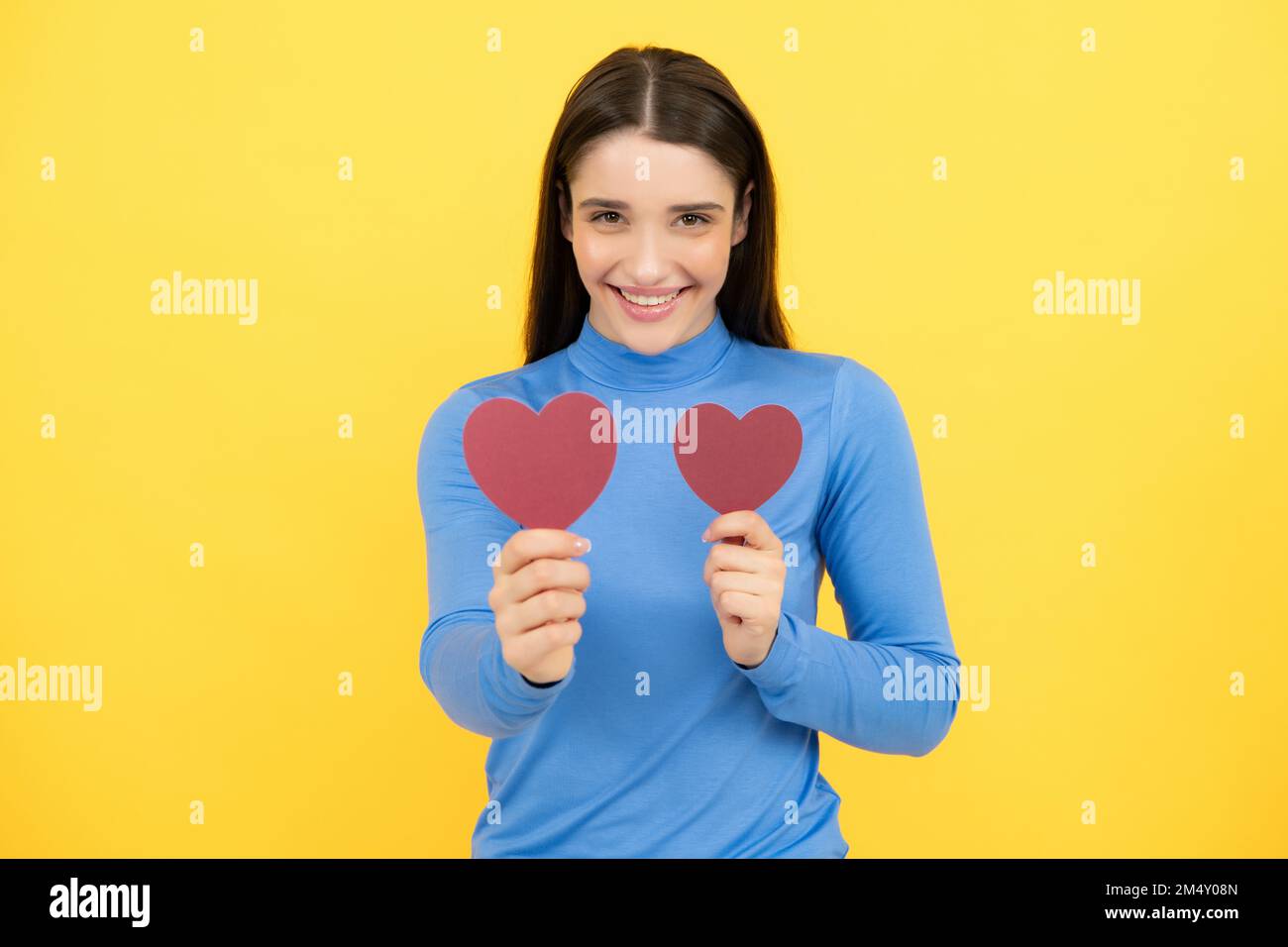 Beautiful amazing woman cuddle paper card heart shape, dreamy isolated on yellow background. Love concept. Valentine day love and beautiful. Stock Photo