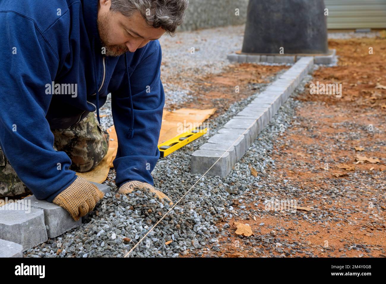 An expert paver worker lays stones on ground for paving of pathway by master. Stock Photo