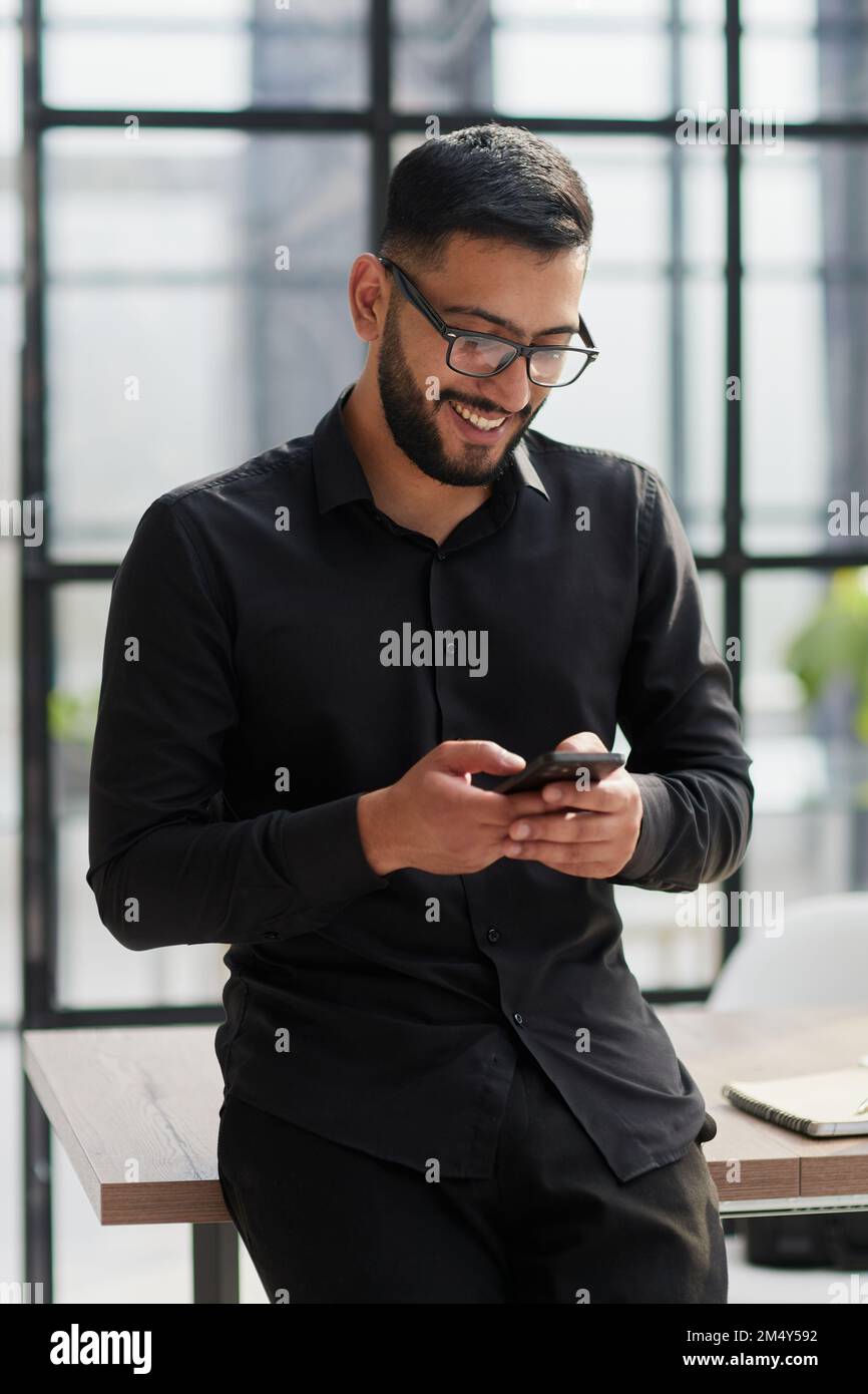 Young casual Businessman holding and using smartphone for sms messages Stock Photo