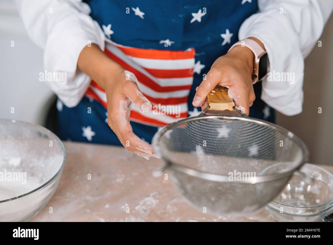 Woman's hands sifting flour through sieve. Selective focus. Stock Photo