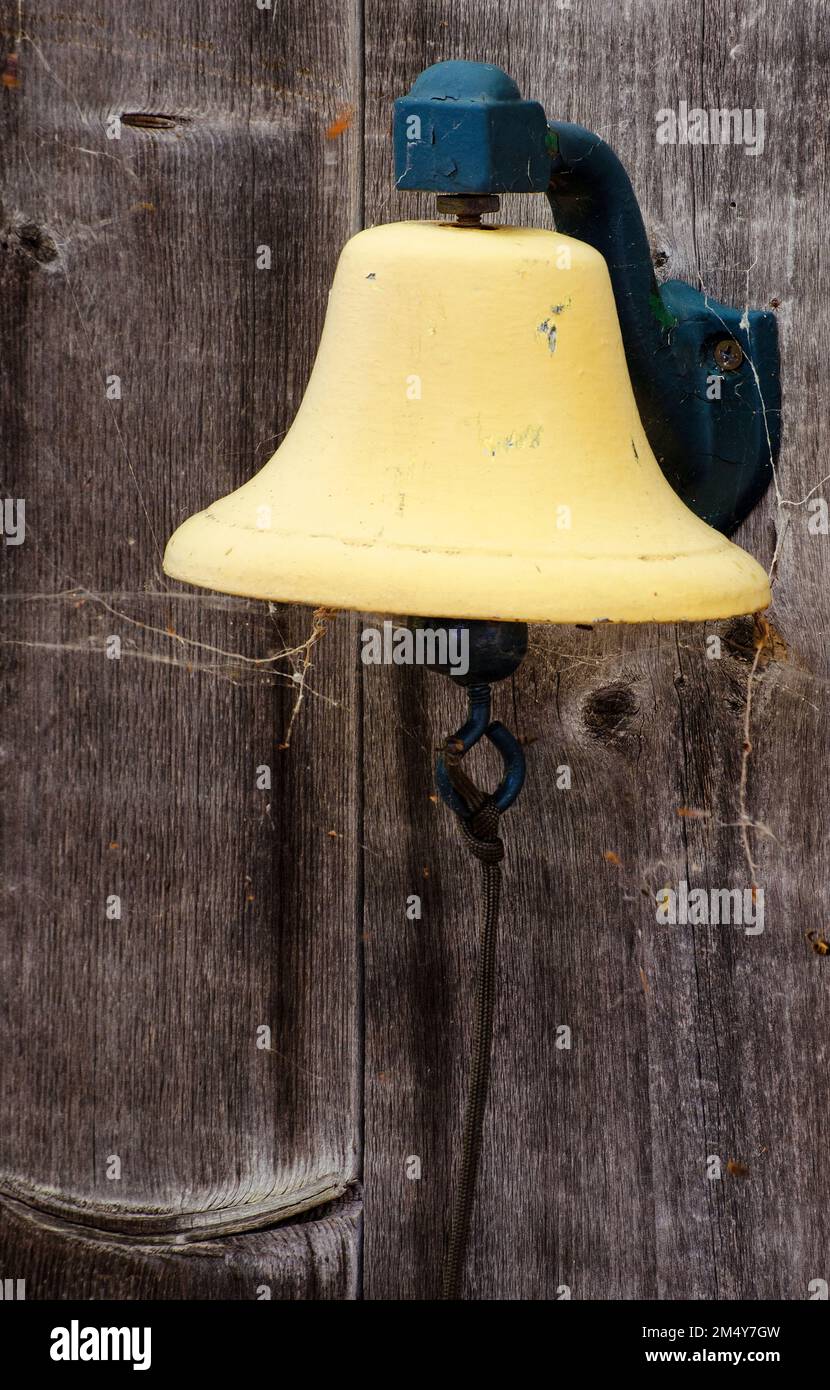 A bell hangs on a storage shed, probably at some point in life a dinner