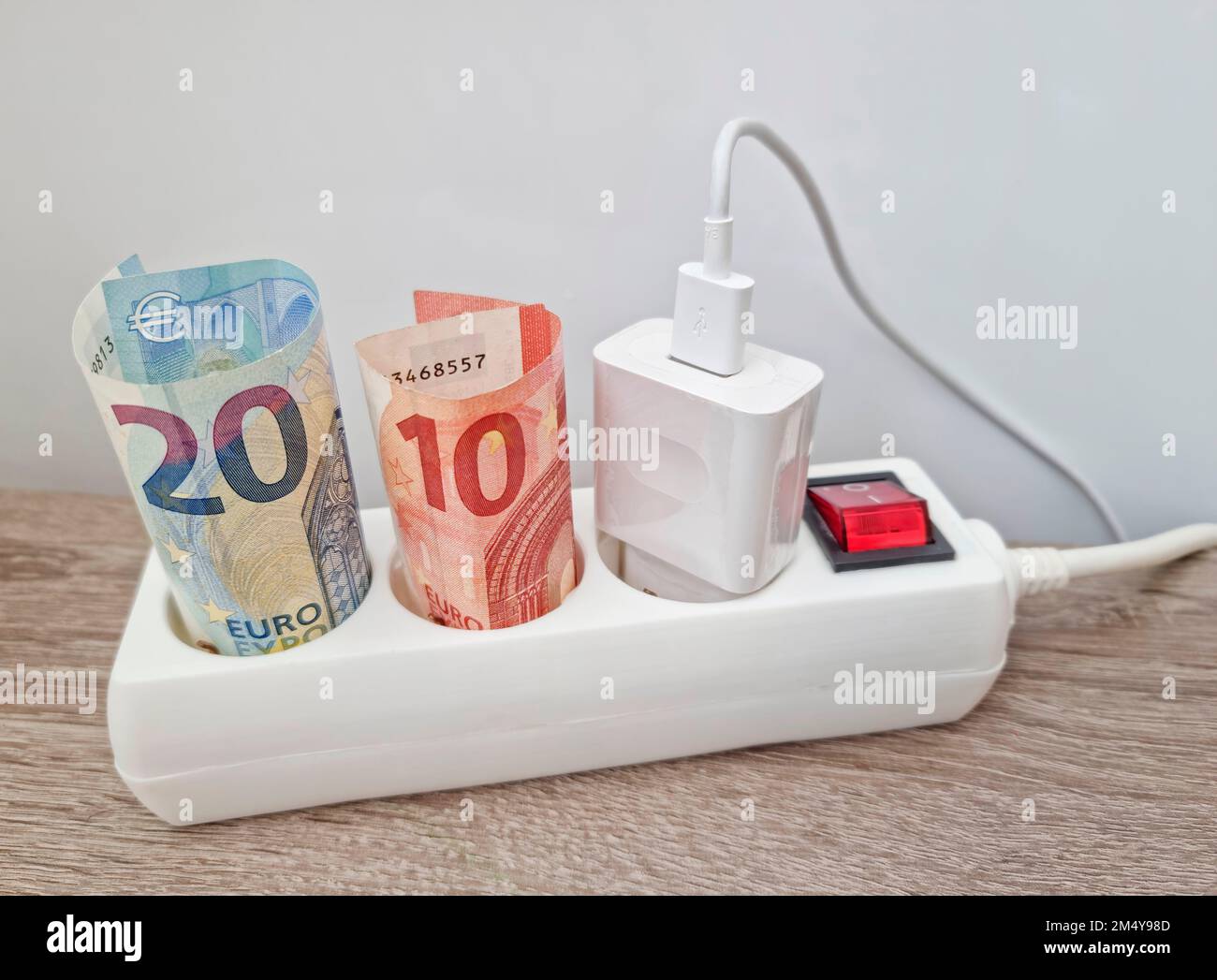 Energy concept with power extension cord and euro currency – the cost of electricity is more expensive due to energy global crisis. Selective focus. Stock Photo