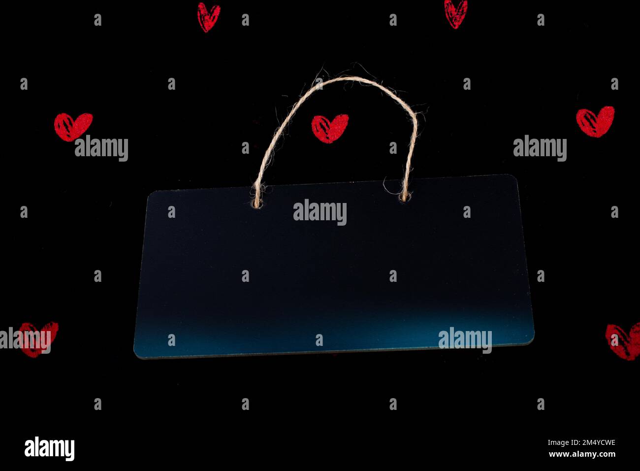 Rectangular shaped black notice board and red hearts on black background Stock Photo