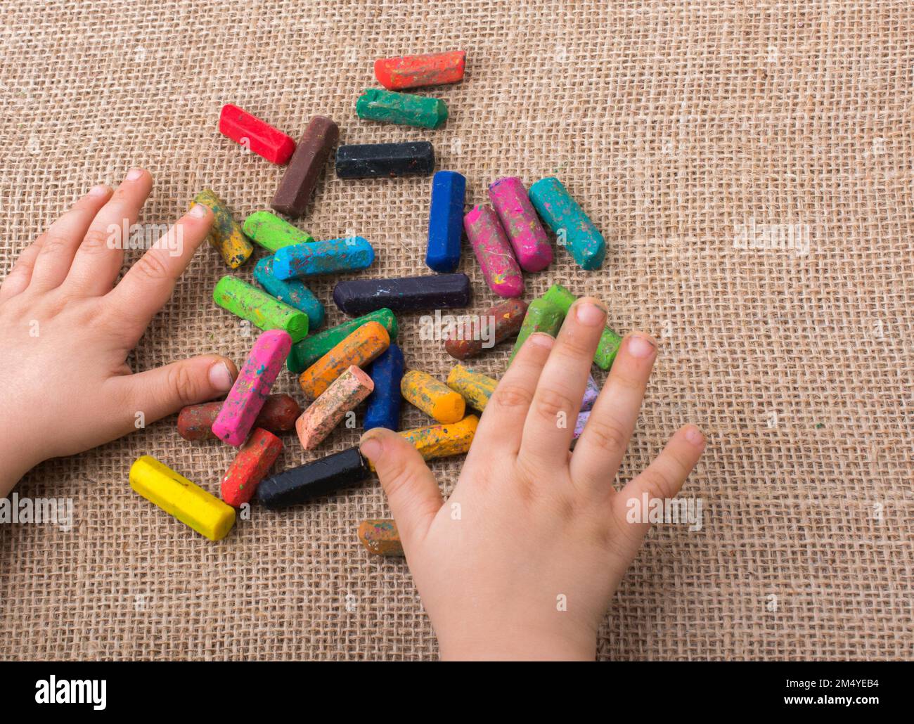 Used color crayons and a toddlers hand holding one Stock Photo Alamy