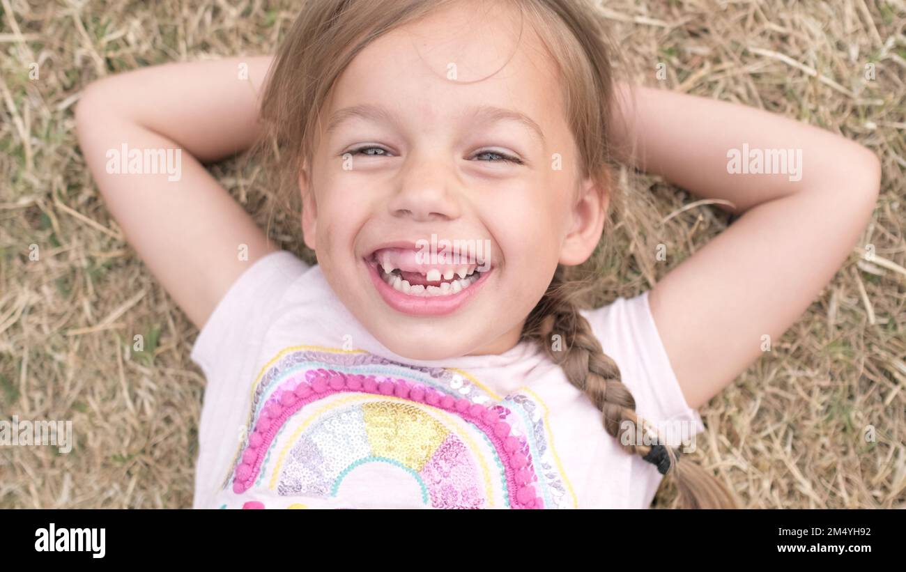 Little Happy toothless and Smiling Child Girl Laying on Yellow Lawn Dry ...