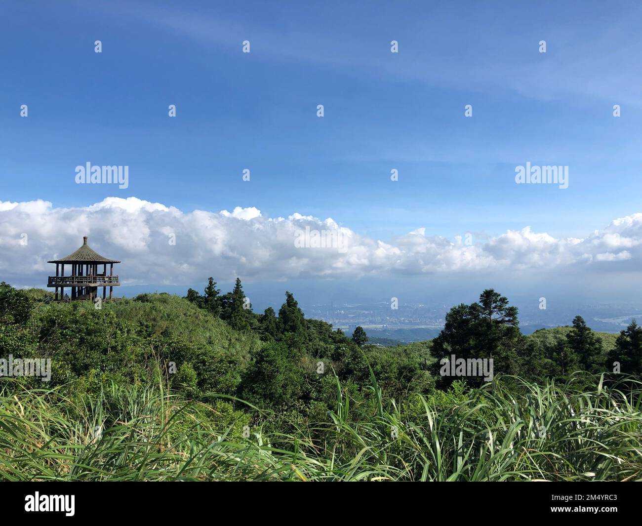 Qixing Mountain in China surrounded by green trees and grass with a watching tower on the peak Stock Photo