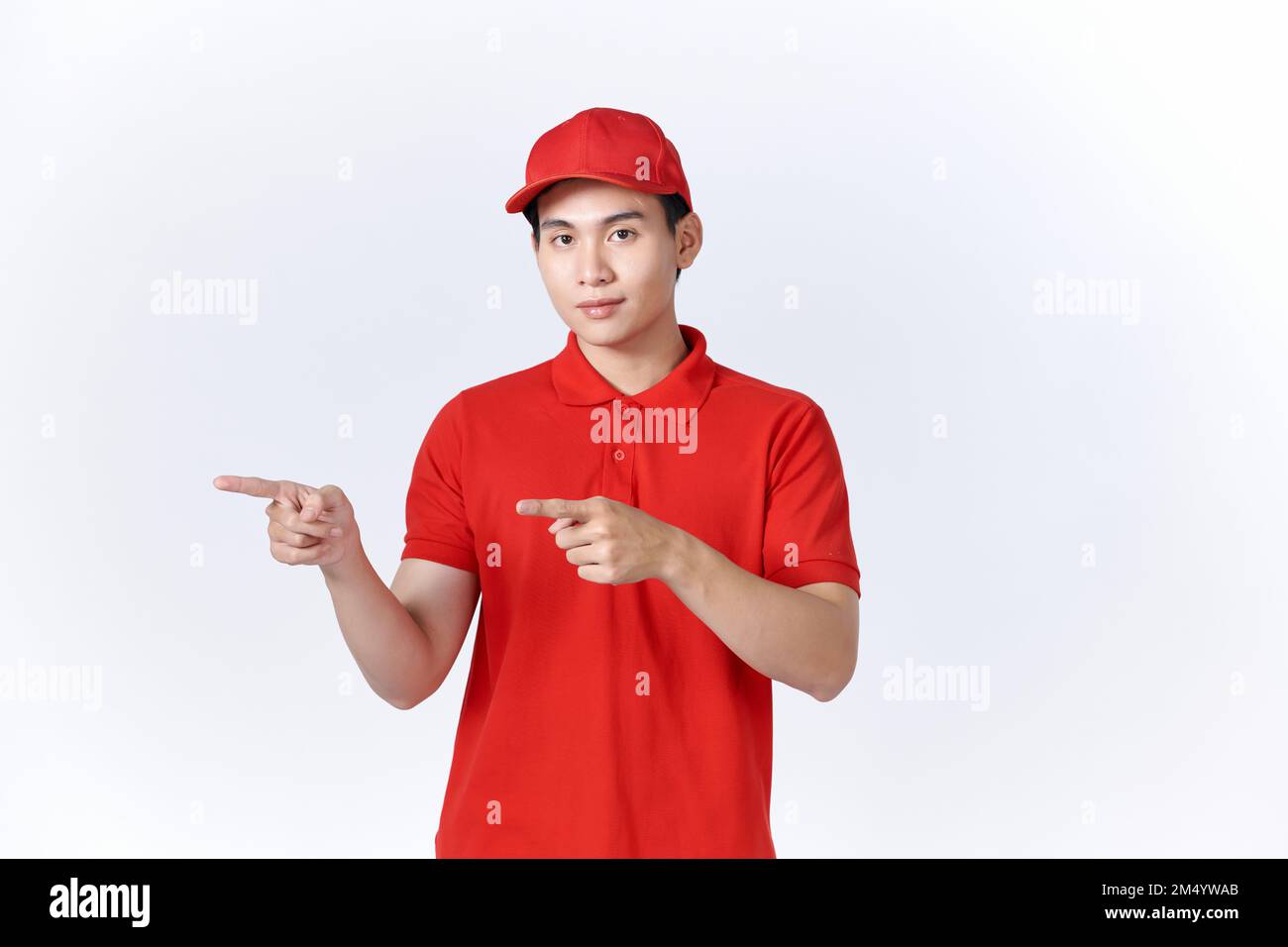 Photo of funny  guy indicate forefingers empty space wear red t-shirt cap isolated white background Stock Photo